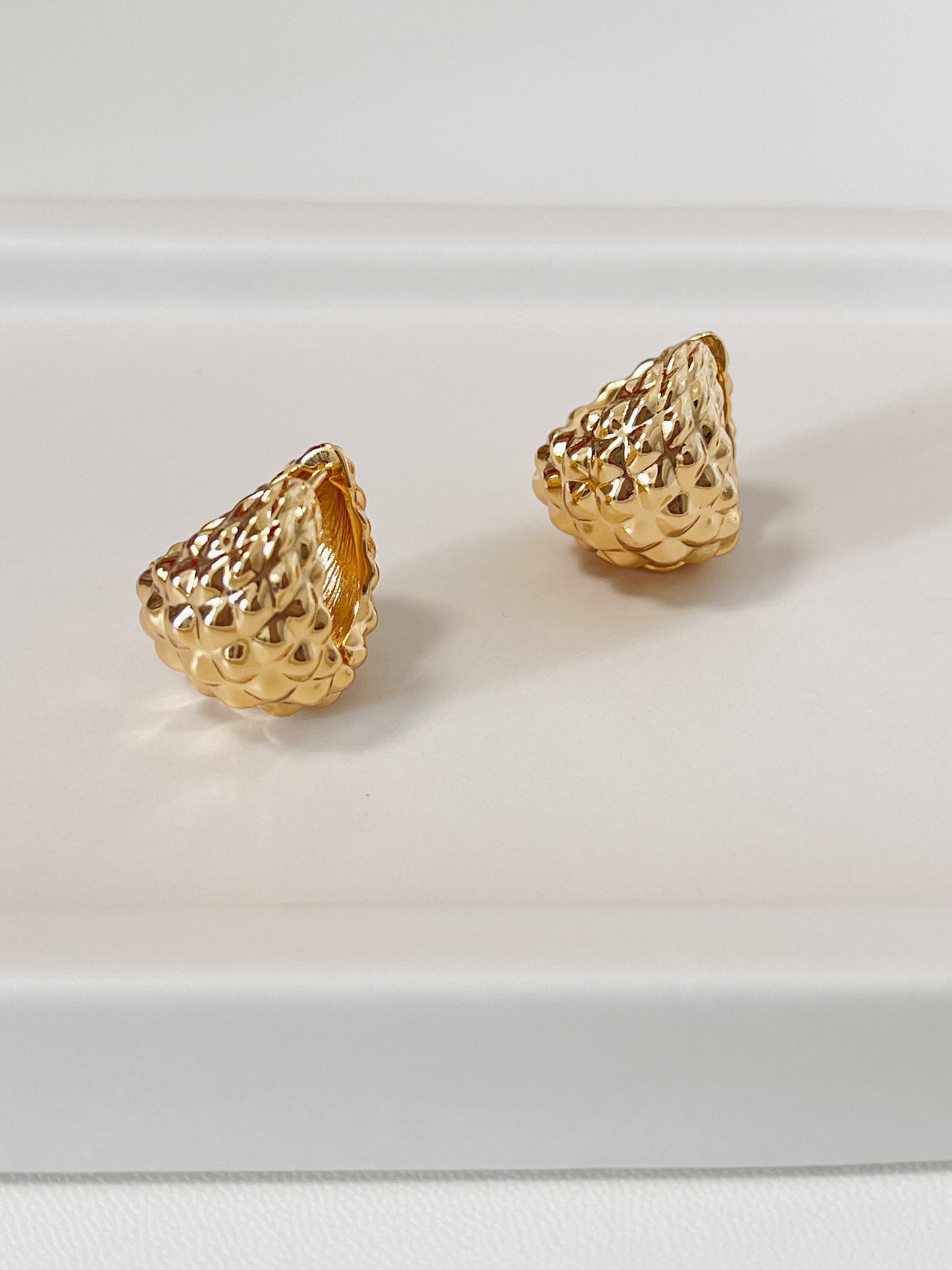 Gold spike textured earrings on a white background