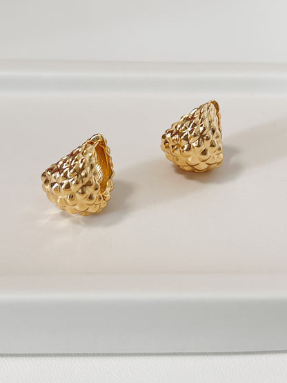Gold spike textured earrings on a white background