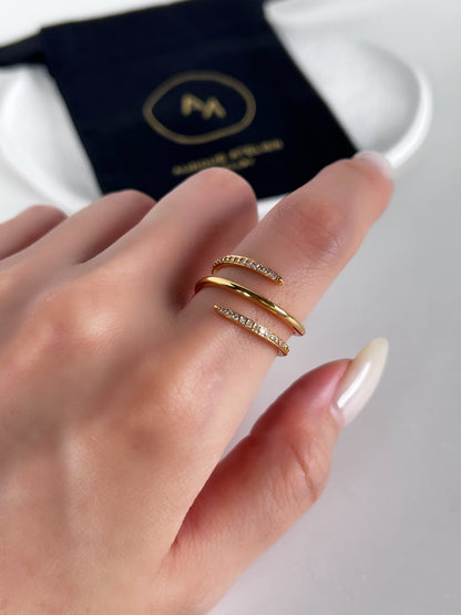 Gold spiral ring on a finger with aurous atelier brand logo in the background