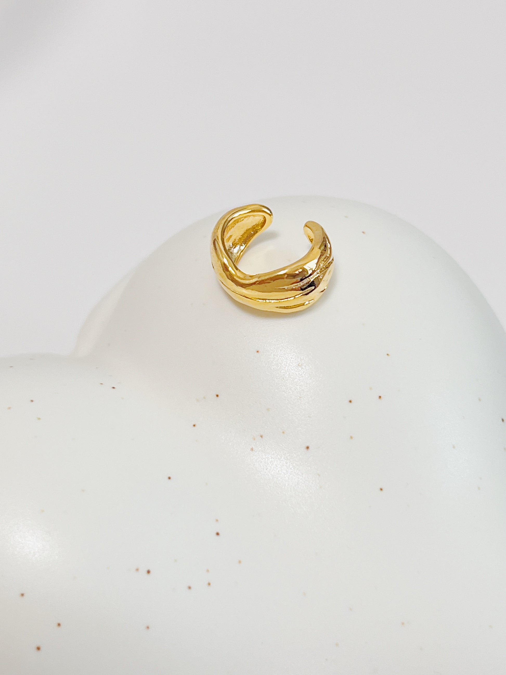 Gold ear cuff on a white surface