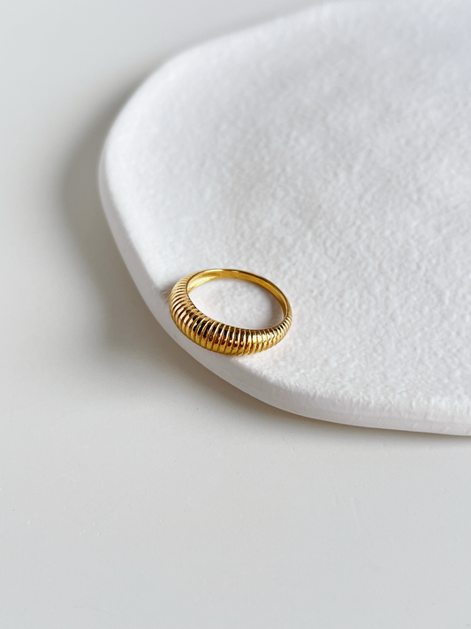 Gold dome ring on a white stone surface