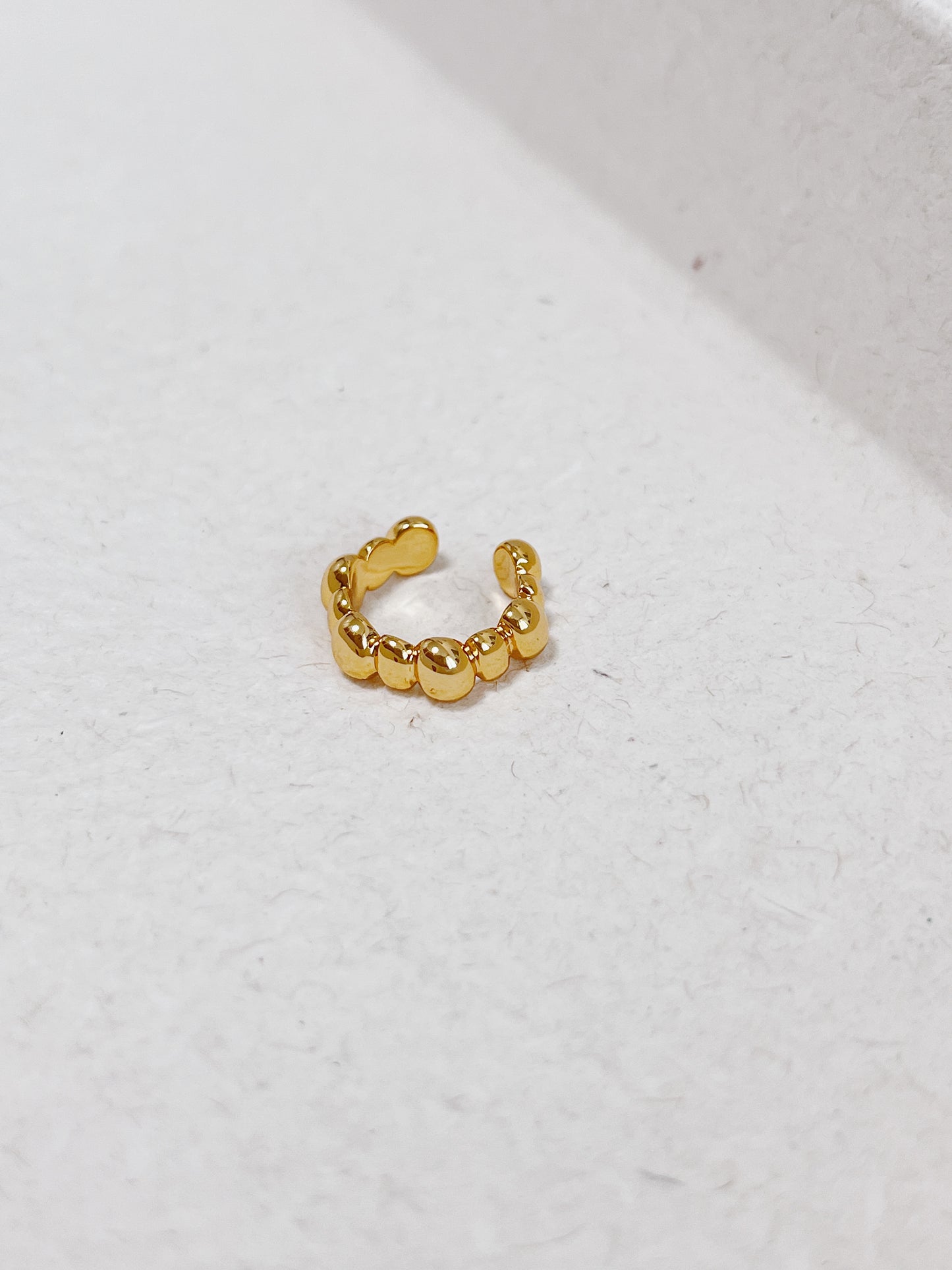 Gold beaded ear cuff on a light gray background