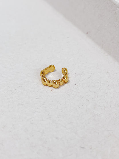 Gold beaded ear cuff on a light gray background