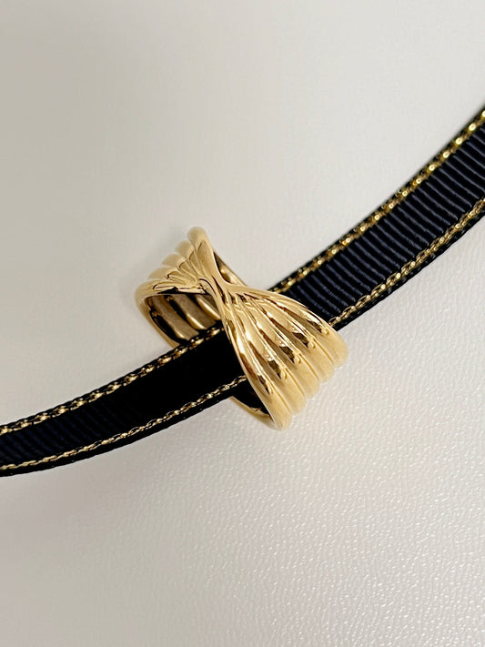 Elegant gold ring with intricate design on black ribbon for luxury jewelry collection.