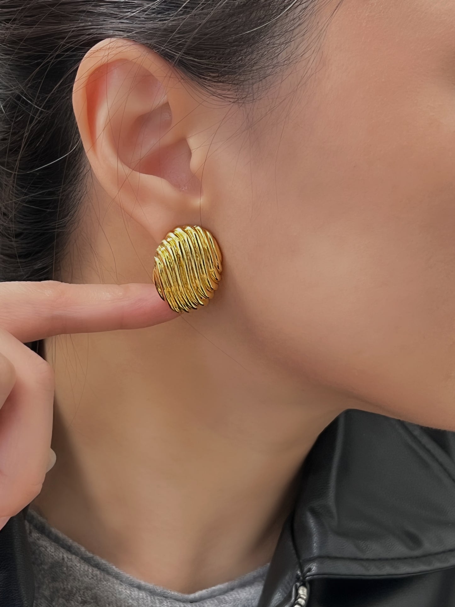 Elegant gold ribbed oval earrings with a shiny, textured finish.