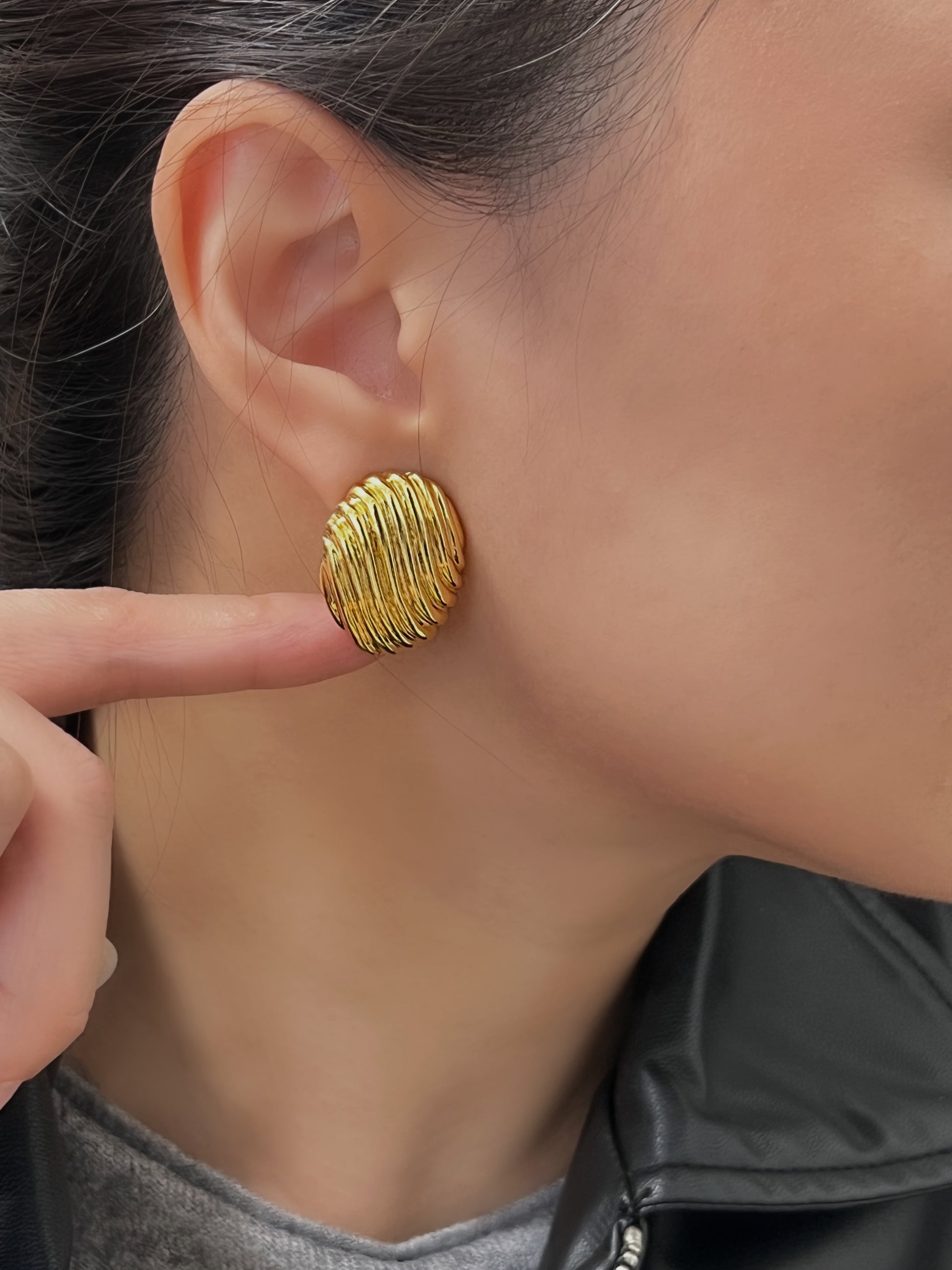 Elegant gold ribbed oval earrings with a shiny, textured finish.