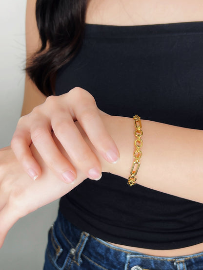 Person wearing a gold bracelet on a plain background