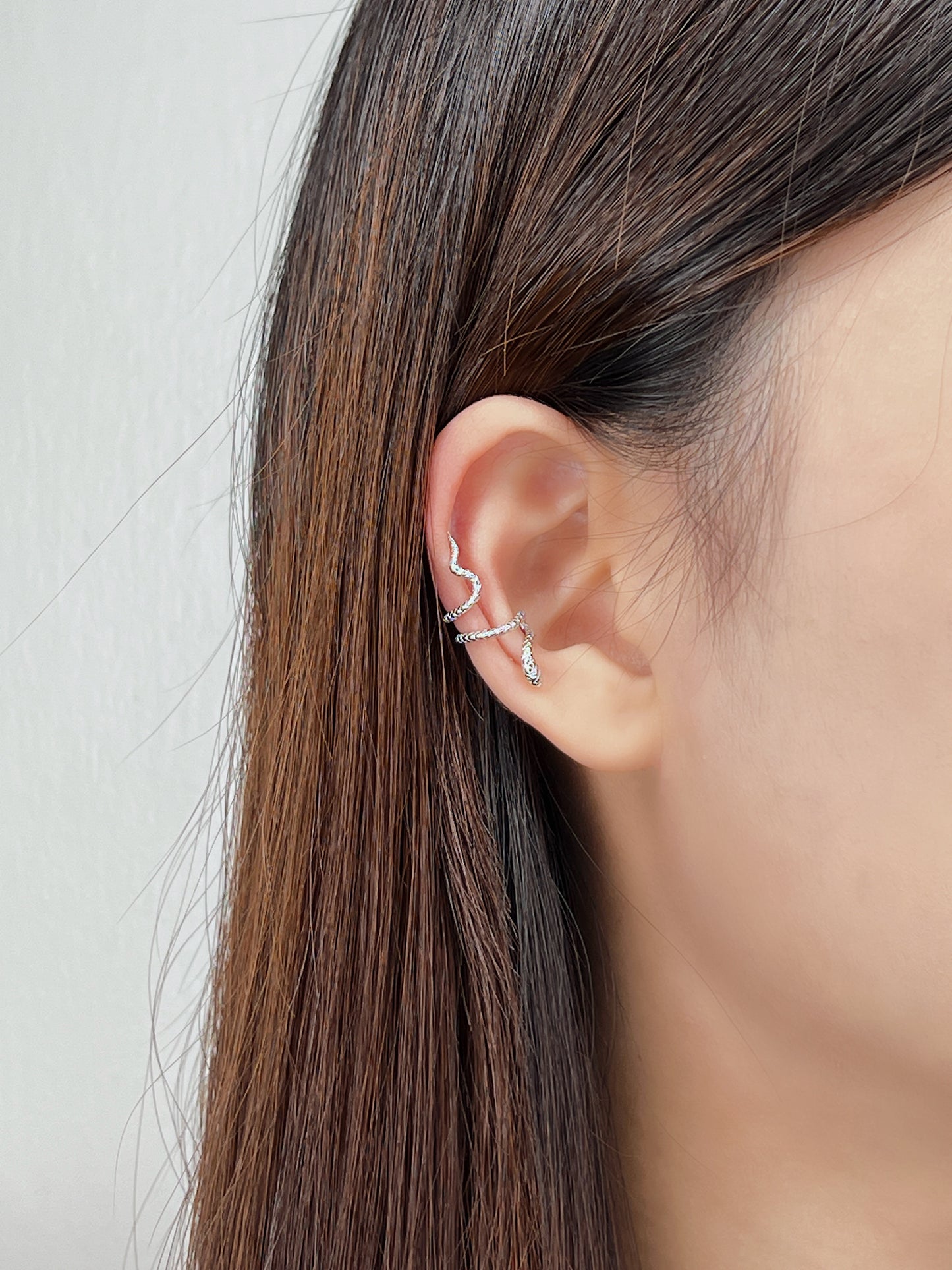 Close-up of an ear wearing a delicate victoria s925 silver serpent ear cuff earring