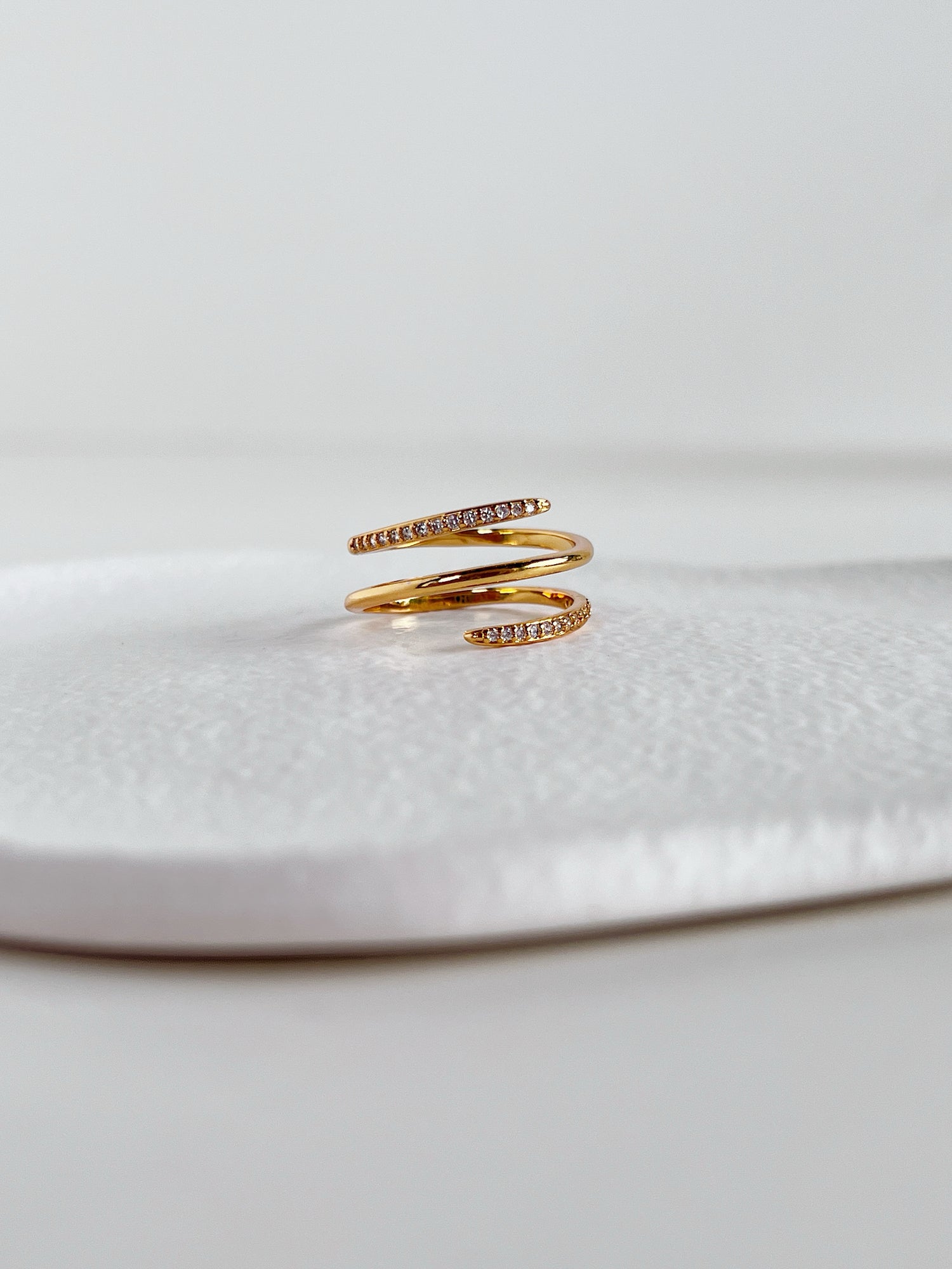 Gold spiral ring with embedded stones on a white surface