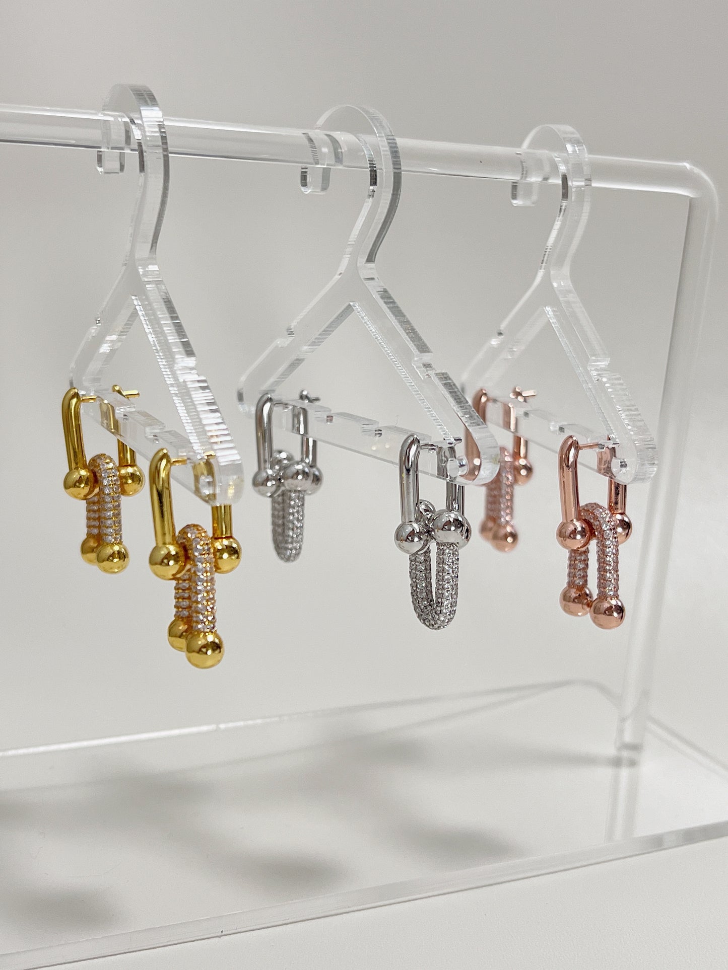 luxurious earrings displayed on a transparent mini jewelry hanger. 