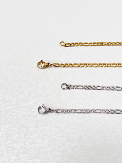 Gold and silver chain necklaces with lobster claps on a light gray background