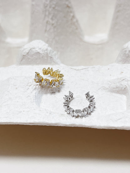 Gold and silver diamond ear cuff on a textured white surface