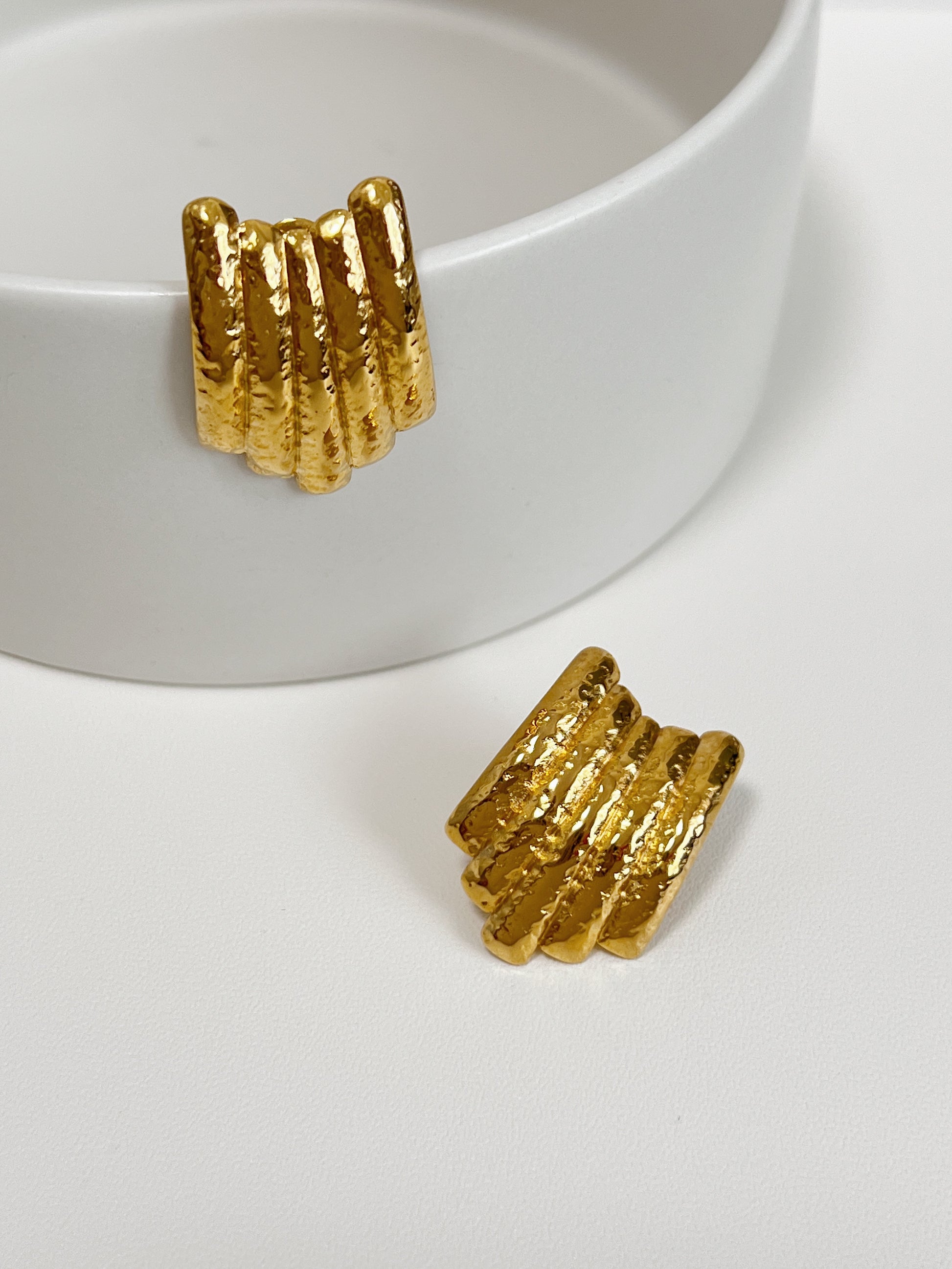 Gold earrings with a textured, hammered finish and ribbed design.