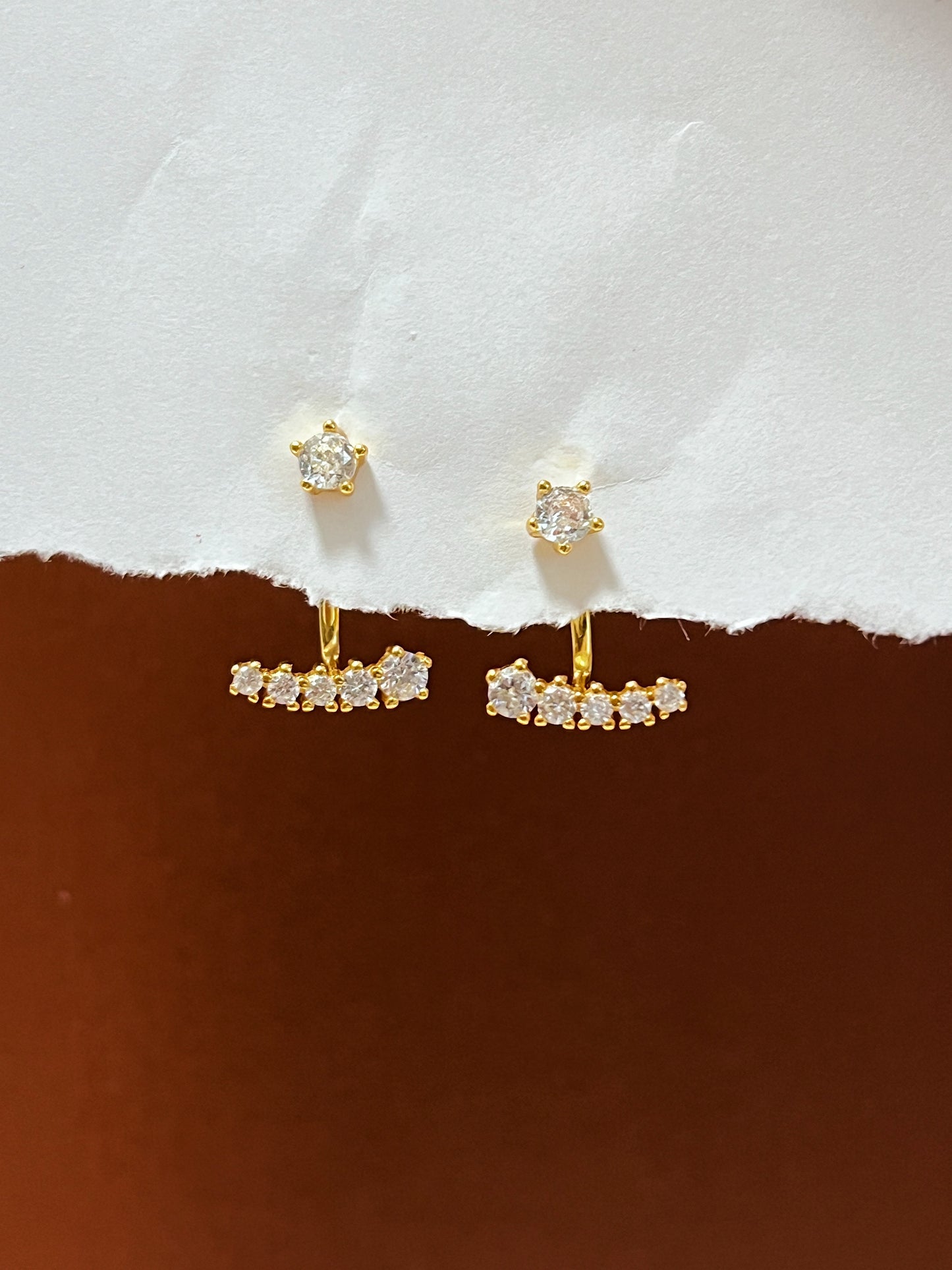 Gold earrings with gemstones on a white and brown background