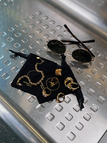 Flat lay aesthetic shot of aurous atelier gold jewelry and amalfi sunglasses