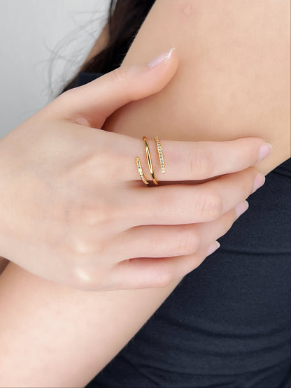 Close-up of a hand wearing gold spiral ring with gemstones with a blurred background