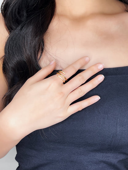 Close-up of a hand wearing a gold cz spiral ring on a plain background
