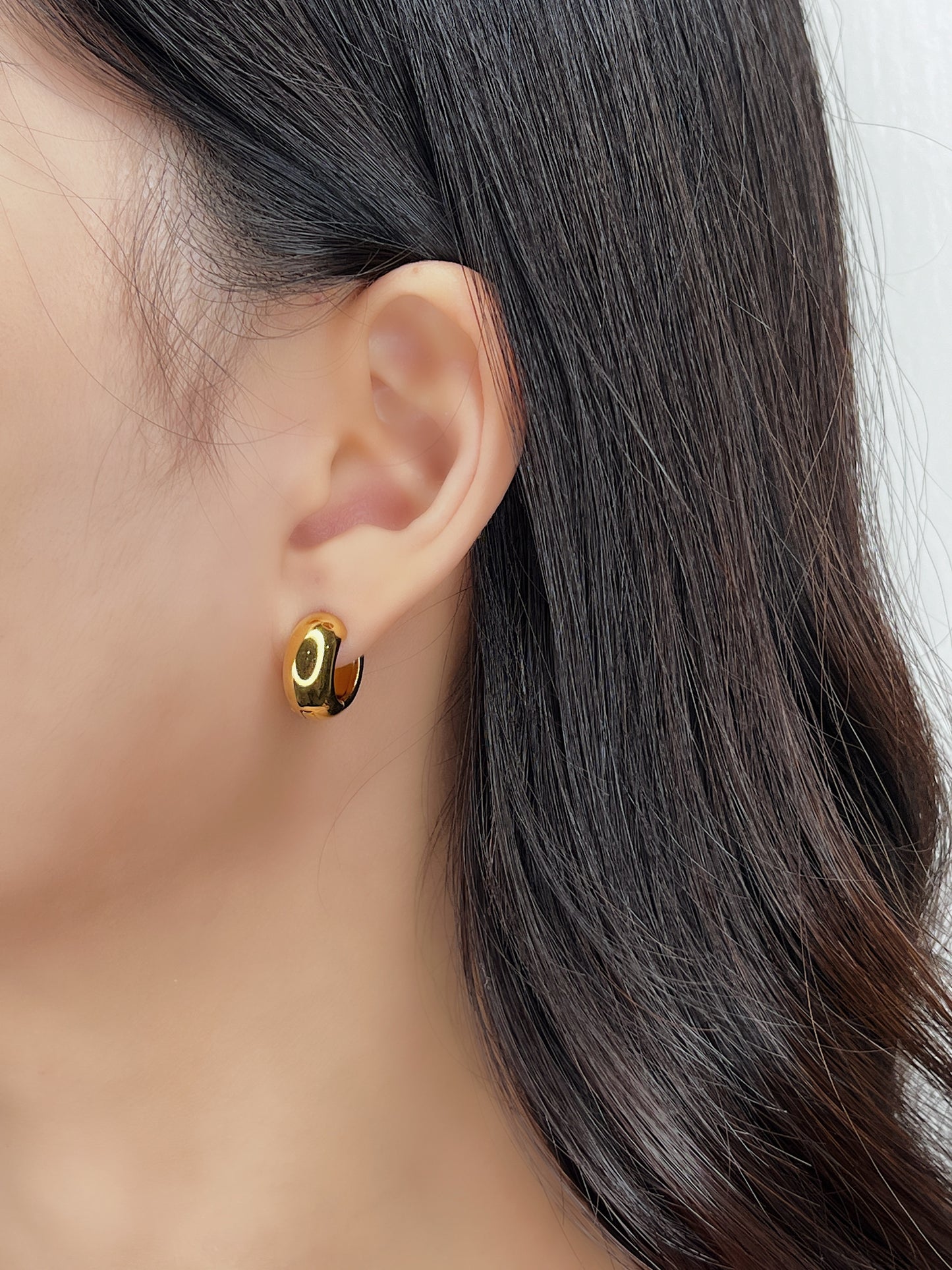 Close up of model's ear showing Amie hoops in 18k gold pvd