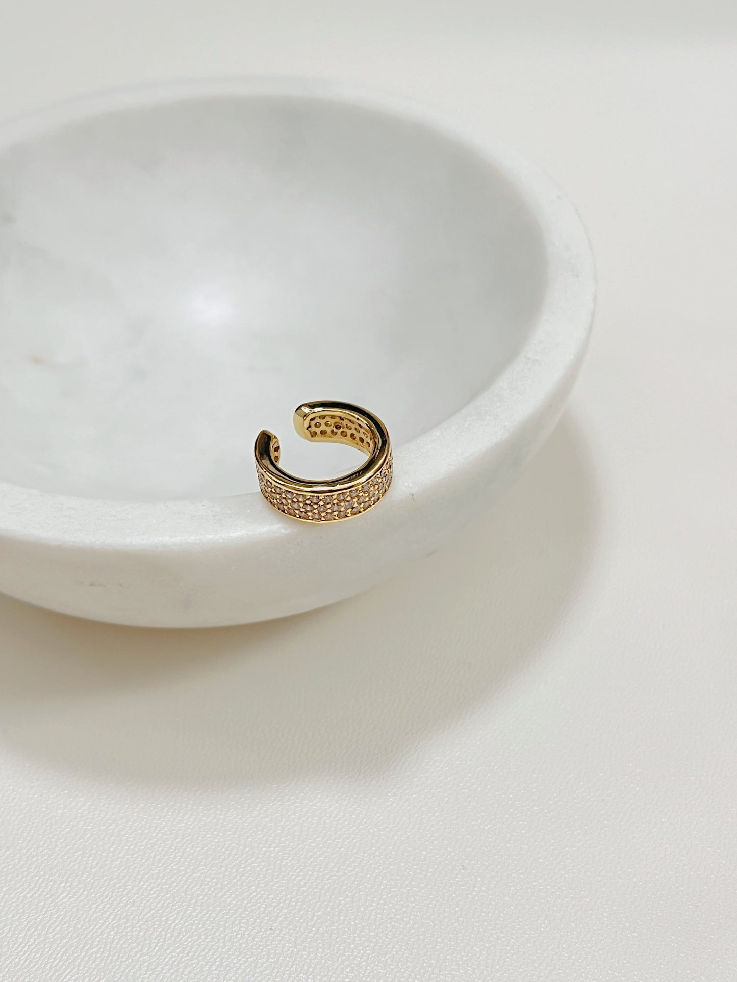 Priscilla Thick Pave Ear Cuff in 14K Gold on the edge of the mini marble sauce bowl