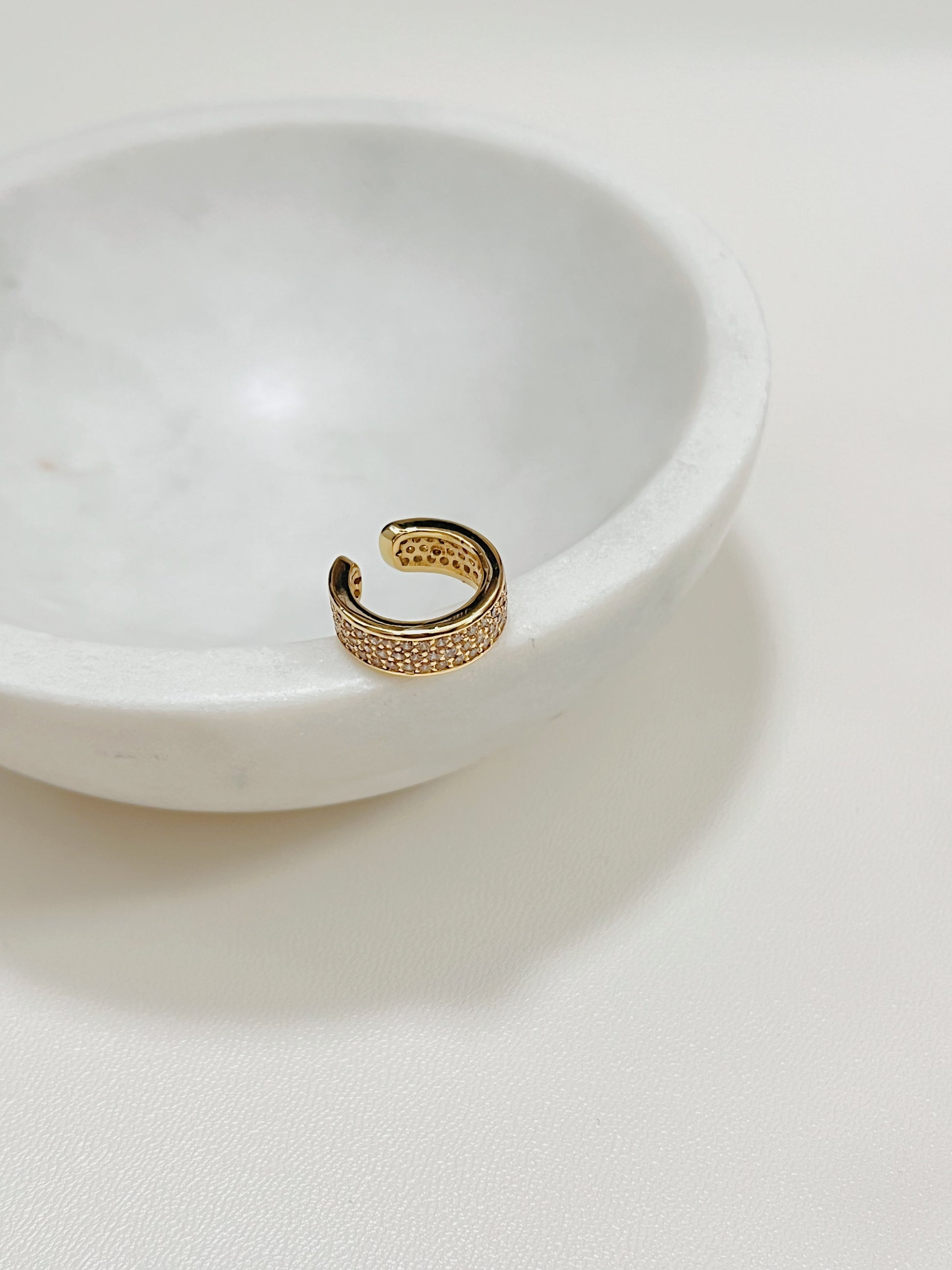 Priscilla Thick Pave Ear Cuff in 14K Gold on the edge of the mini marble sauce bowl