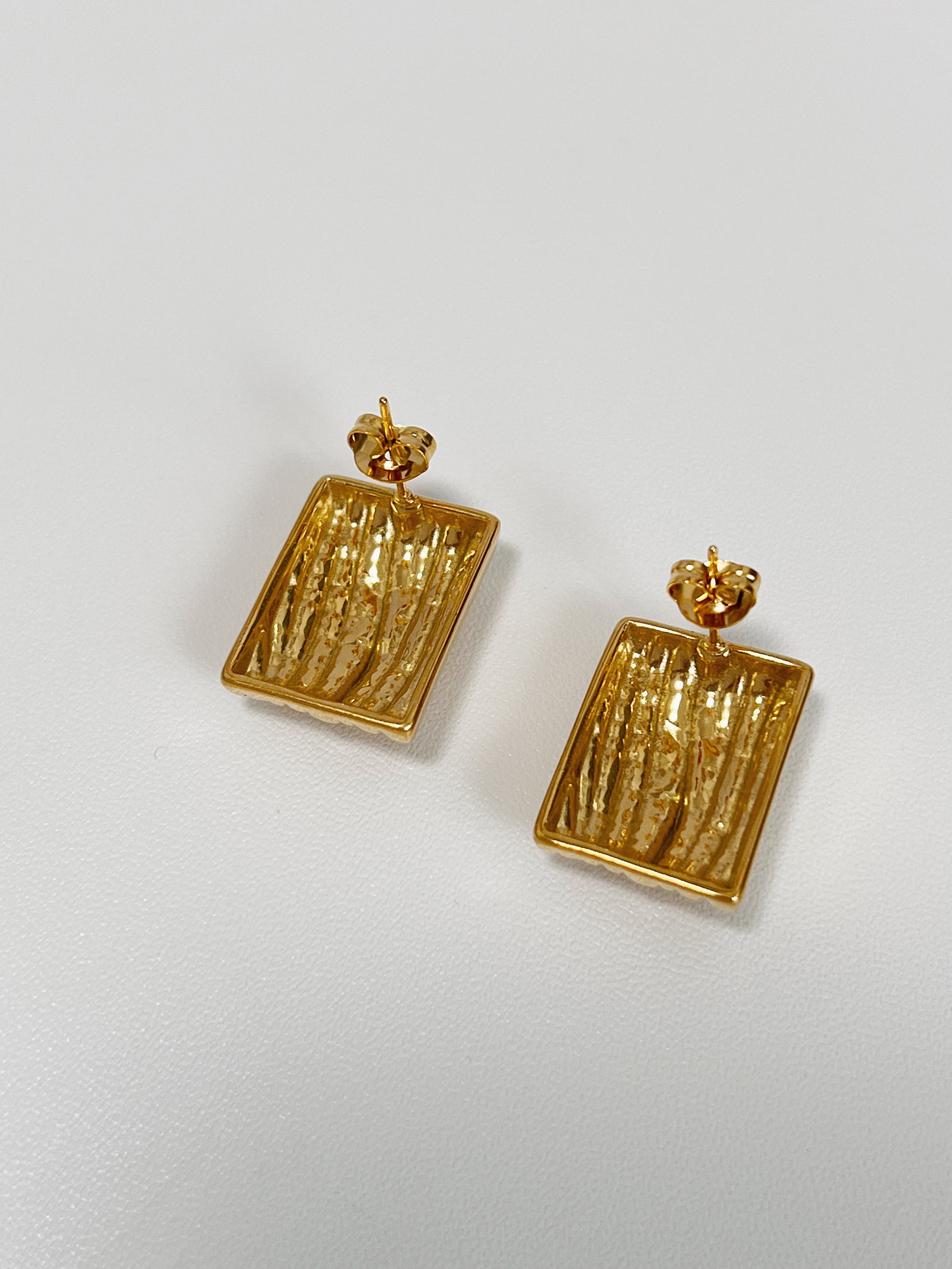 Rectangular gold earrings with a unique texture.