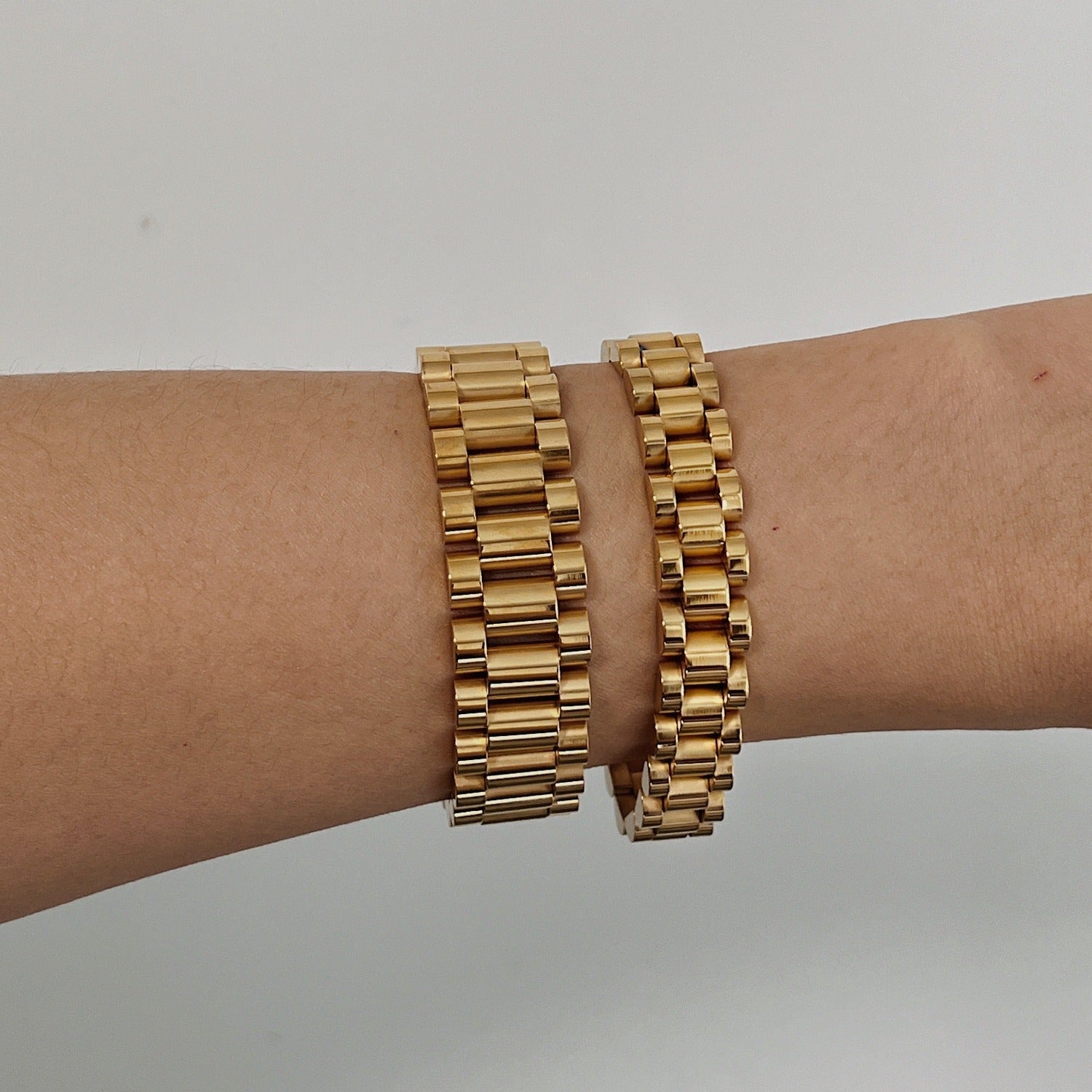 Side-by-side comparison of the 15mm wide (left) and 10mm standard (right) Spencer watch link bracelets in gold on a wrist.