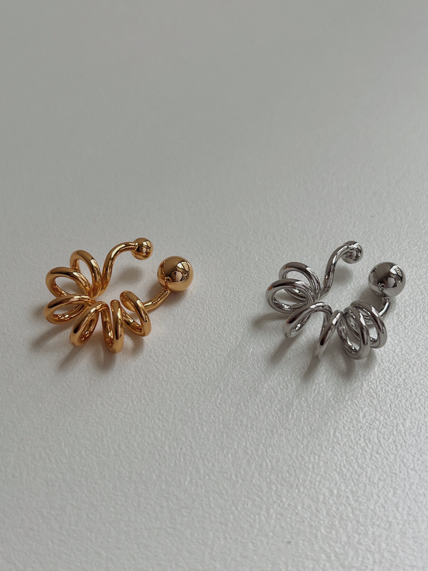 Gold and silver Lis cuffs side-by-side to highlight the liquid-mirror finish.