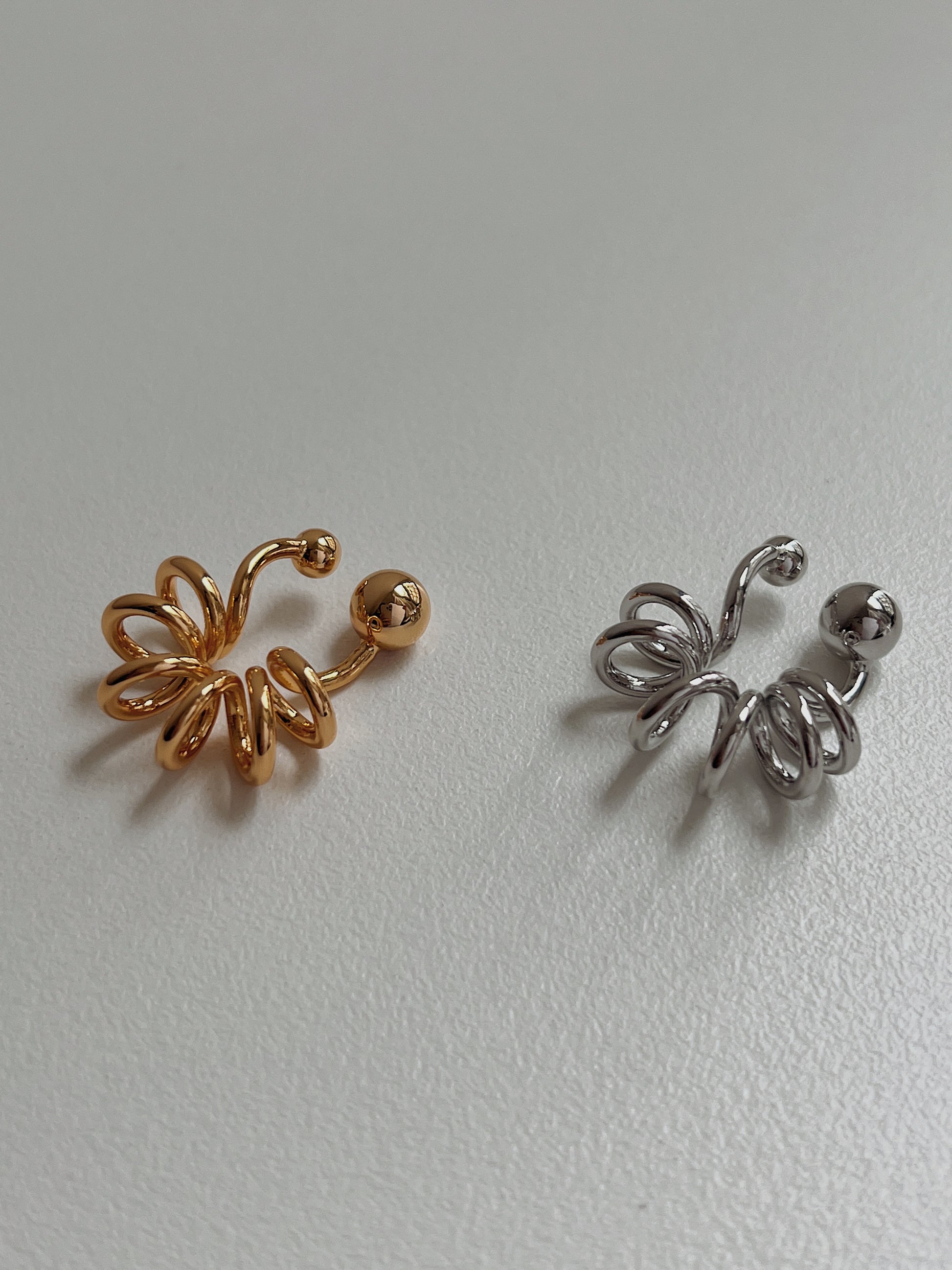 Gold and silver Lis cuffs side-by-side to highlight the liquid-mirror finish.