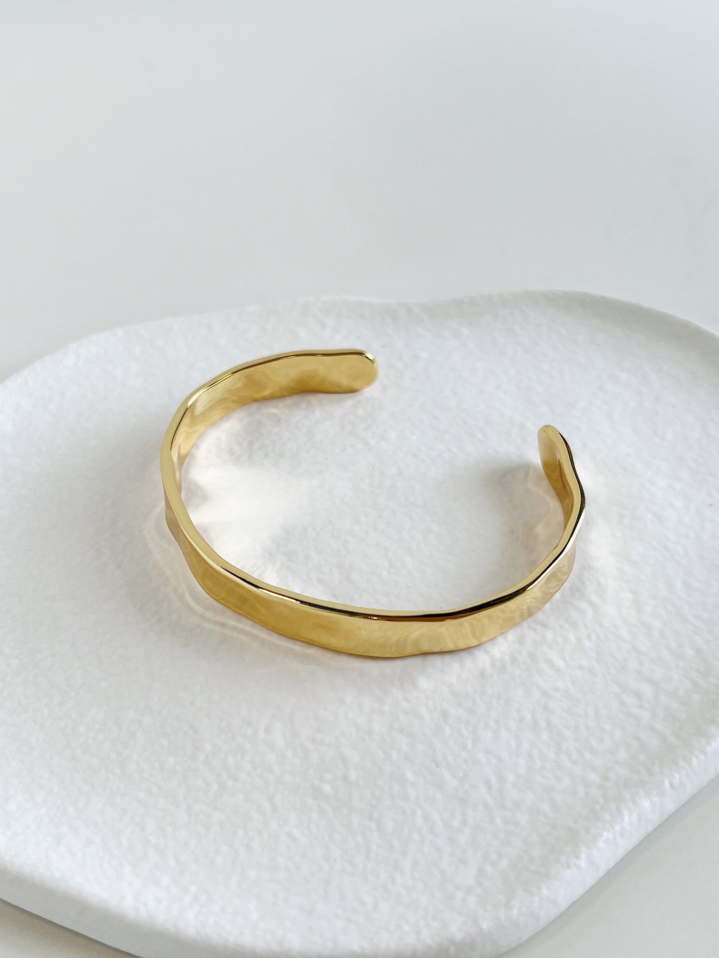 Side view highlighting the slightly adjustable open gap design of a heavy-gauge gold plated cuff bangle.