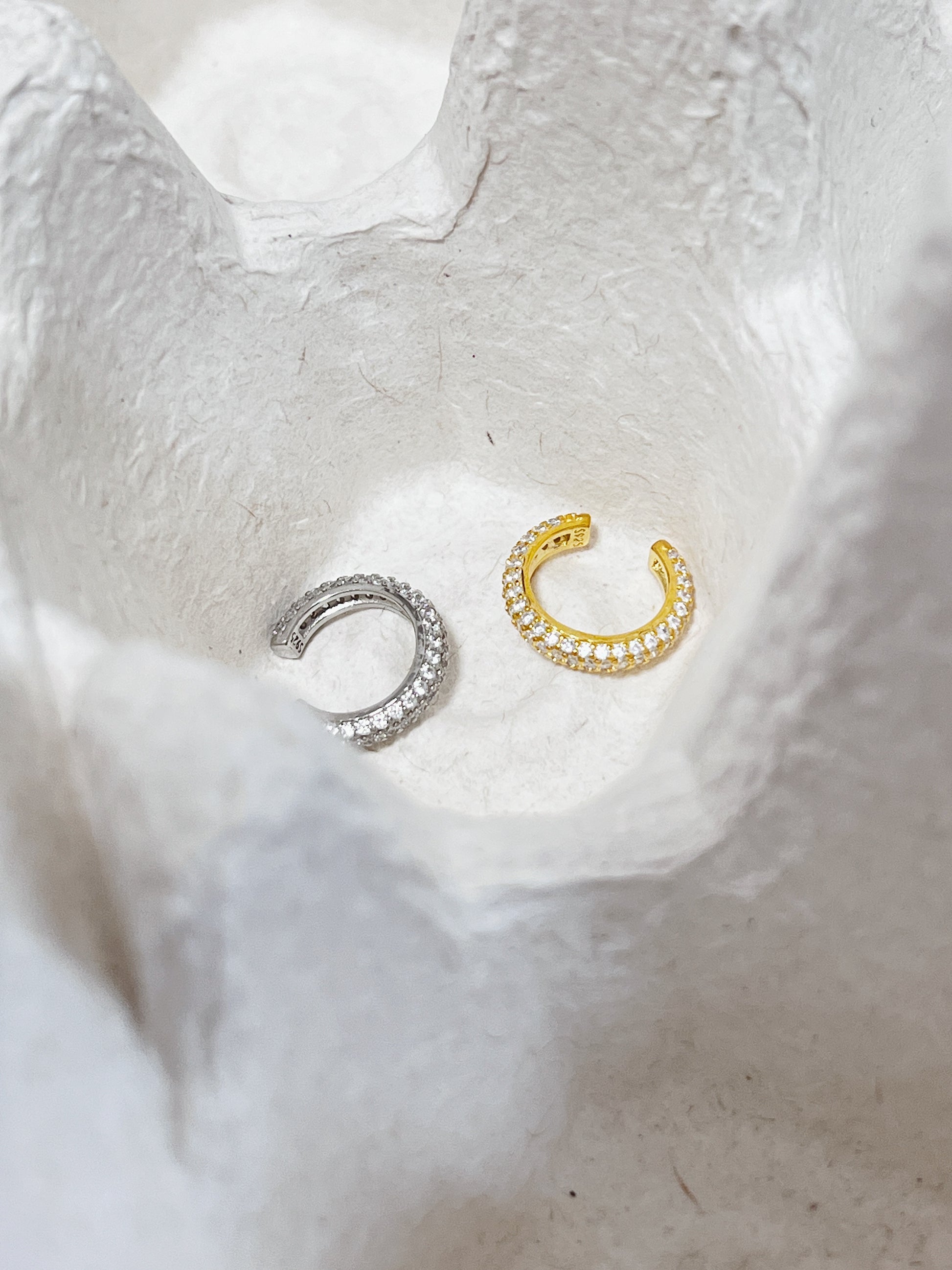 Macro photography of the Rose Pavé Ear Cuff showcasing the seamless triple-row crystal setting and high-shine 18K gold finish.