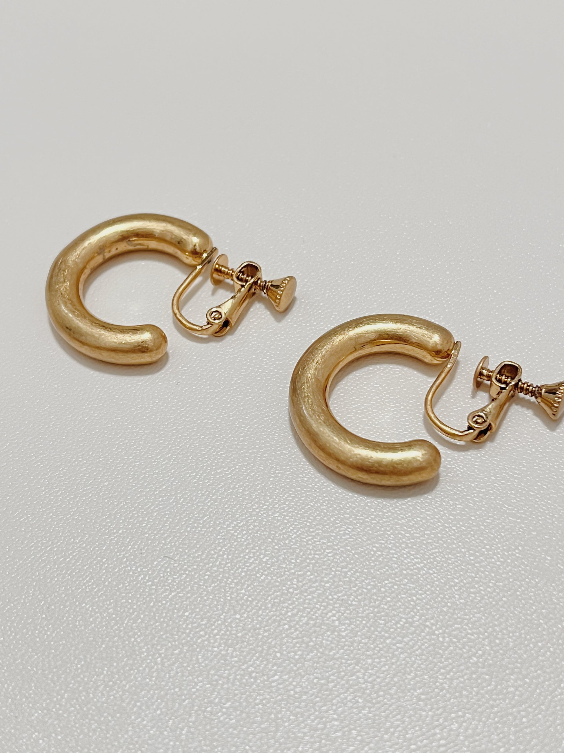 Technical close-up showing the premium adjustable screw hinge backing of the gold Zora clip-on hoop earrings.