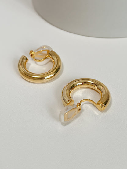 Close up perspective of adjustable clip on hoops showcasing transparent resin comfort pads
