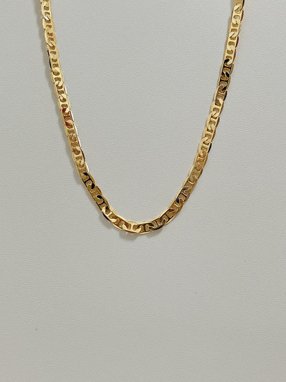 Studio view of the Alba mariner chain necklace showing its flat 4mm gold geometric link profile on a white leather background