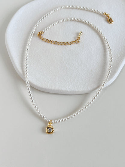 Overhead view of the Alta pearl necklace showcasing its uniform 4mm seed pearl strand on a white textured porcelain dish