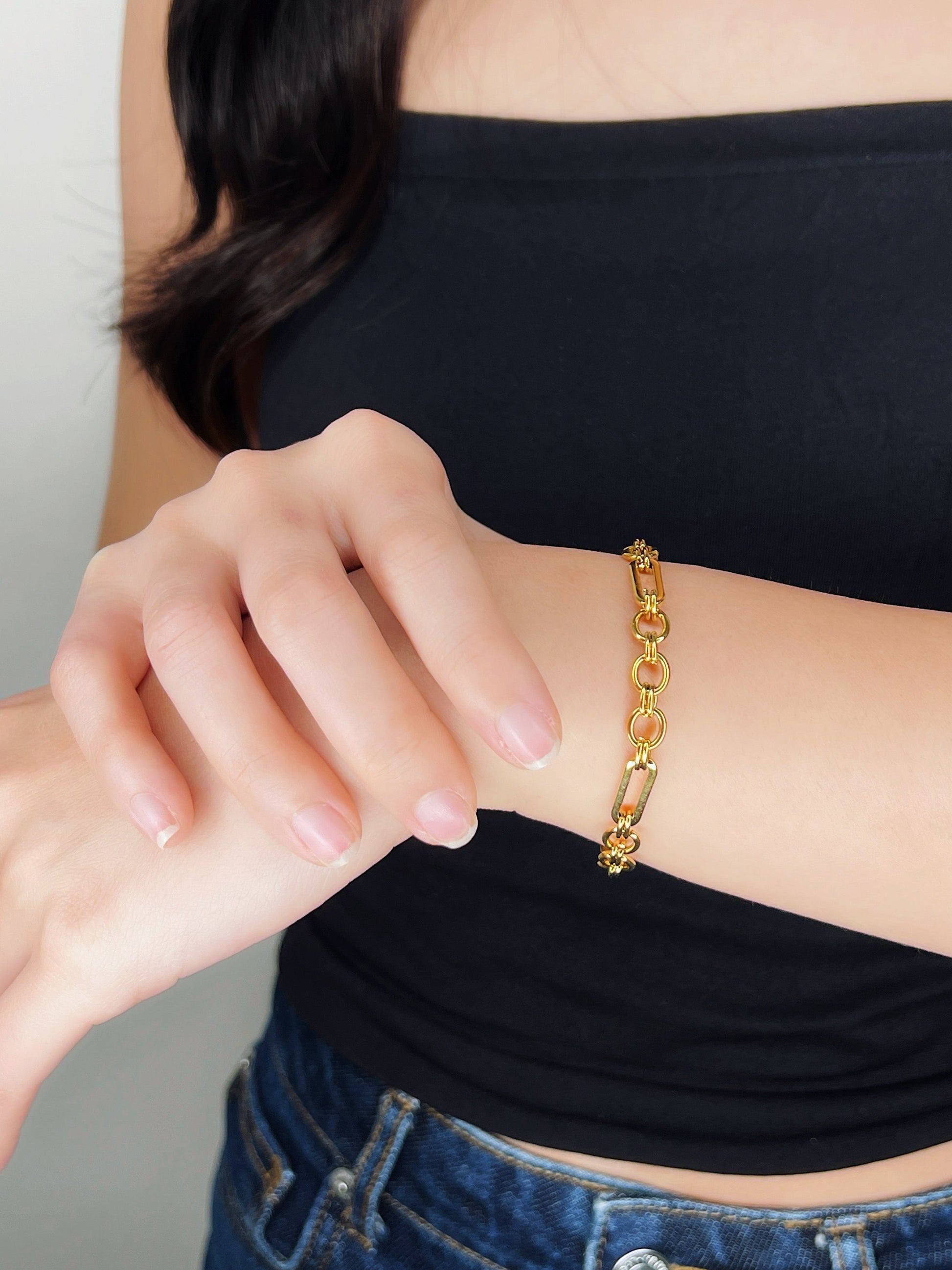 Close-up shot of a model's arm showing the Alyssa gold PVD structural bracelet sitting elegantly on her wrist bone while her hand rests softly against her skin