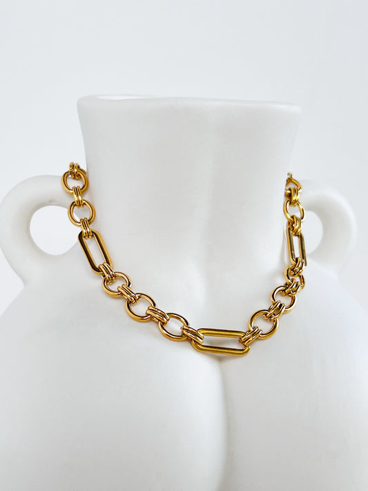 Close-up view of the Alyssa mixed link chain bracelet draped over the front curves of a white ceramic female bust vase, highlighting the alternating geometric links.