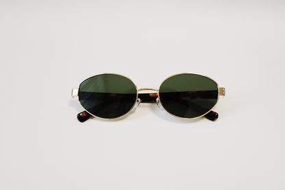 The Amalfi sunglasses folded flat on a stone display tray, showcasing the thick tortoiseshell panels and low-profile layout.