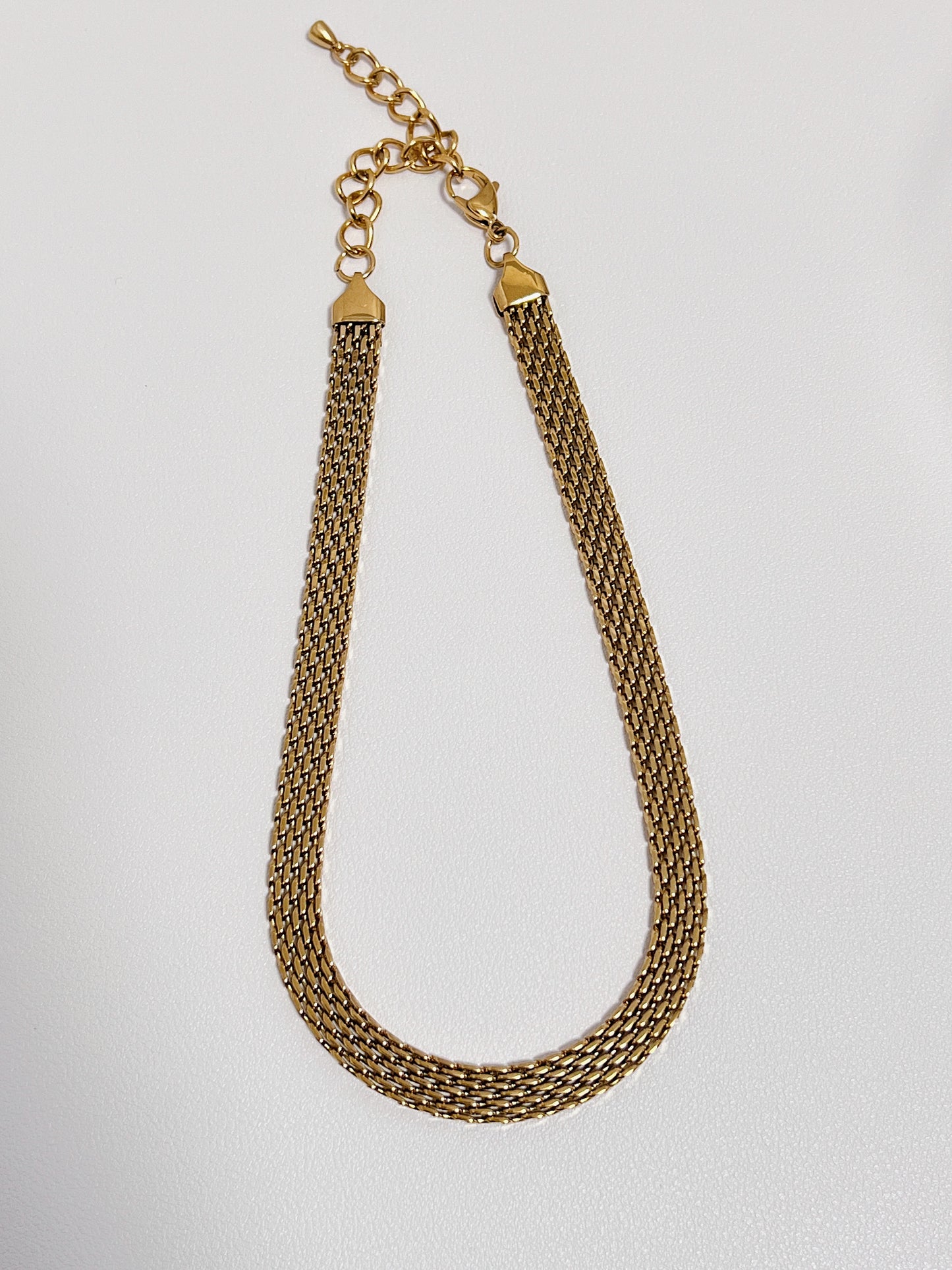 Symmetrical layout of an architectural 8mm woven gold chain highlighting its fluid fabric like flexibility