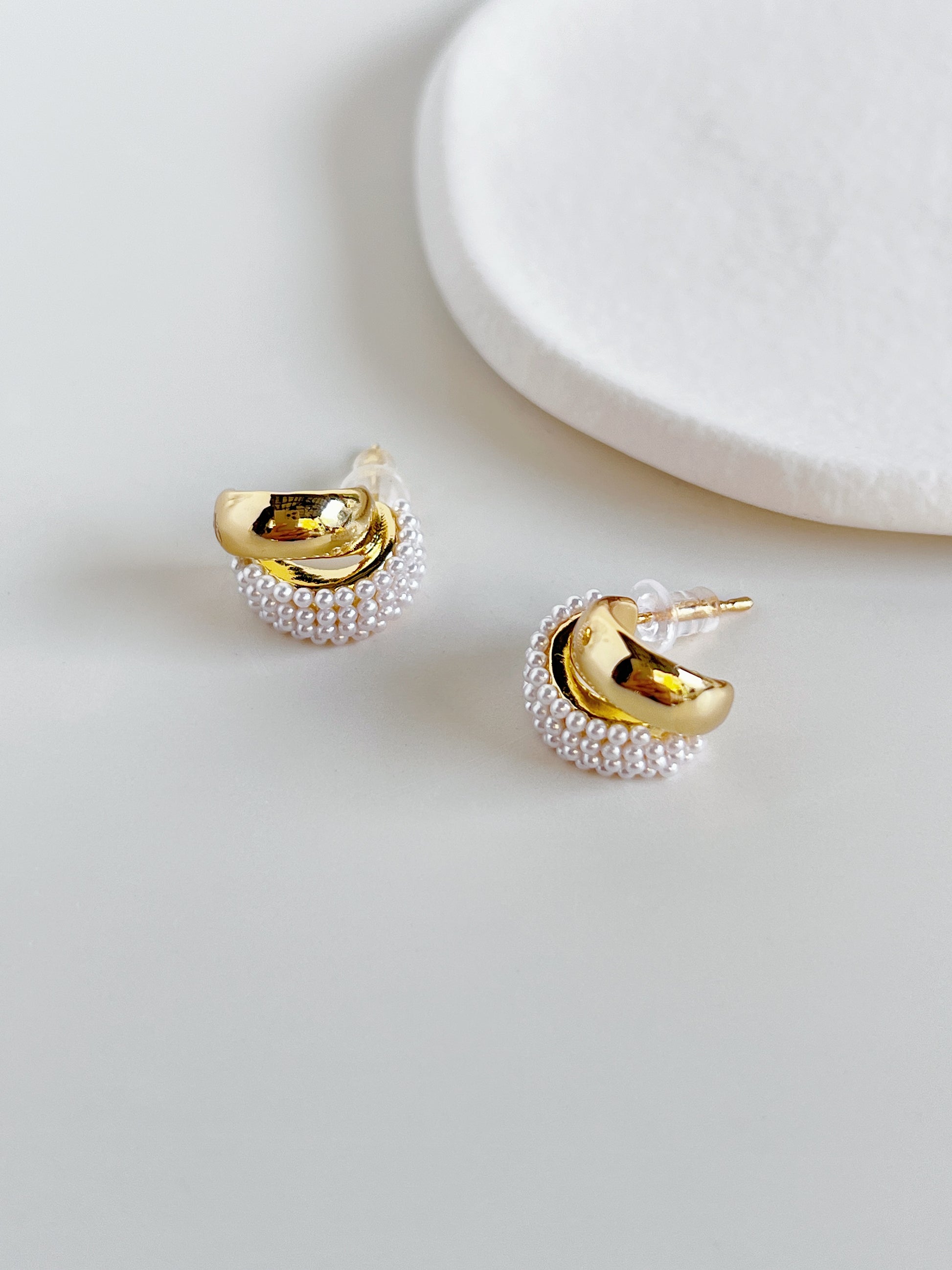 Close up of premium 18k gold PVD smooth band nested next to micro seed pearls