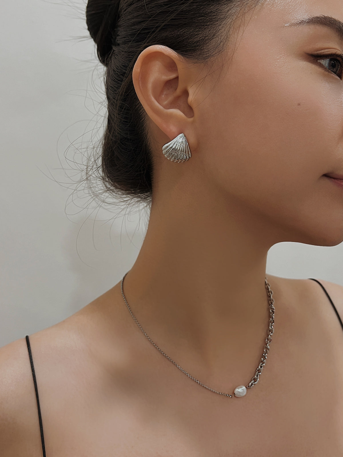 Close up shot of model featuring non-pierced Ariel gold shell stud and pearl chain necklace