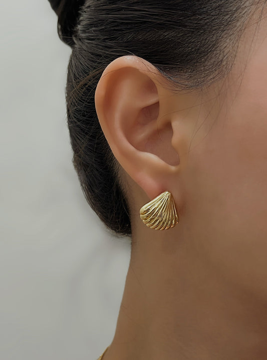 Close up of a model wearing Ariel gold shell clip-on stud earrings