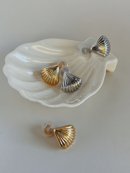 Ambient light reflecting off fluted scalloped architecture of Ariel gold and silver shell clip-on earring