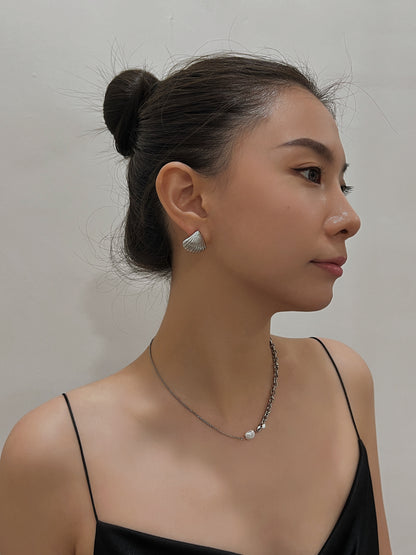 Model wearing Ariel silver shell clip-on stud earrings with a black dress