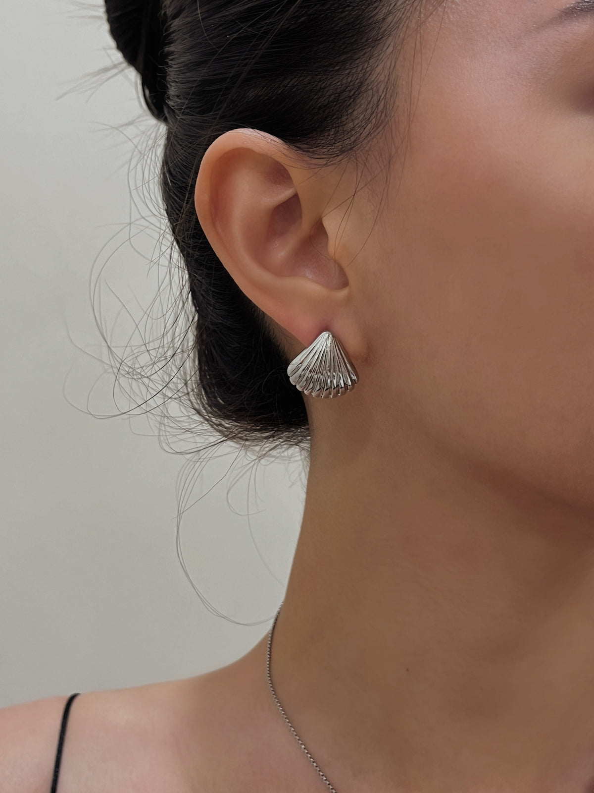Close up shot of a model wearing Ariel silver shell clip-on stud earrings