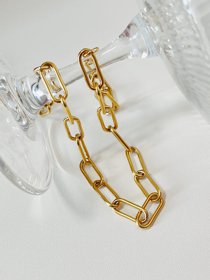 Structural view of Asher gold paperclip chain wrapped around the stem of an inverted crystal glass, showcasing how the links fluidly catch light.