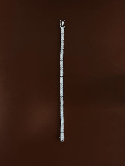 Full-length overhead view of the silver Astra channel set tennis bracelet featuring 3mm square princess-cut stones laid straight on an espresso background to display total length and continuous sparkle for capsule wardrobe jewelry stacks.