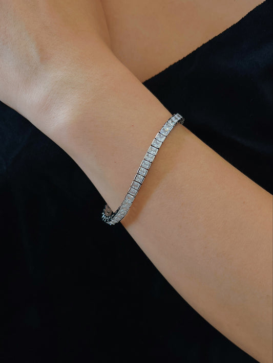 Angle wrist perspective showing the Astra square tennis bracelet draped gracefully against a black dress, reflecting a clean line of light for sophisticated evening wear styling.