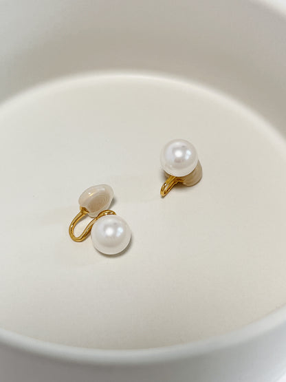 Overhead view of a pair of 10mm floating pearl clip-on stud earrings crafted with high-shine gold wire clips.