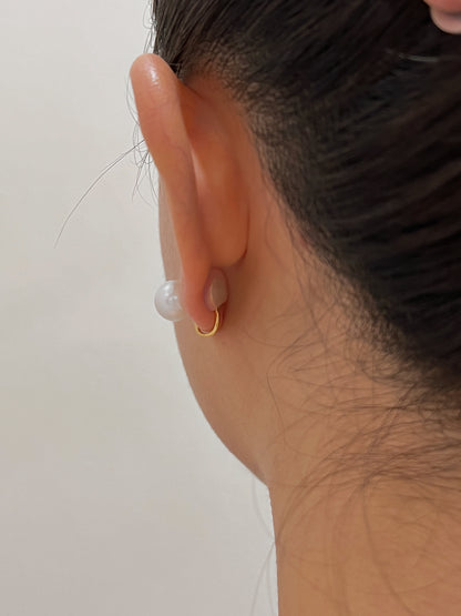 Back view of earlobe showing invisible gold wire clip and clear silicone pad holding a 10mm pearl stud without piercings.