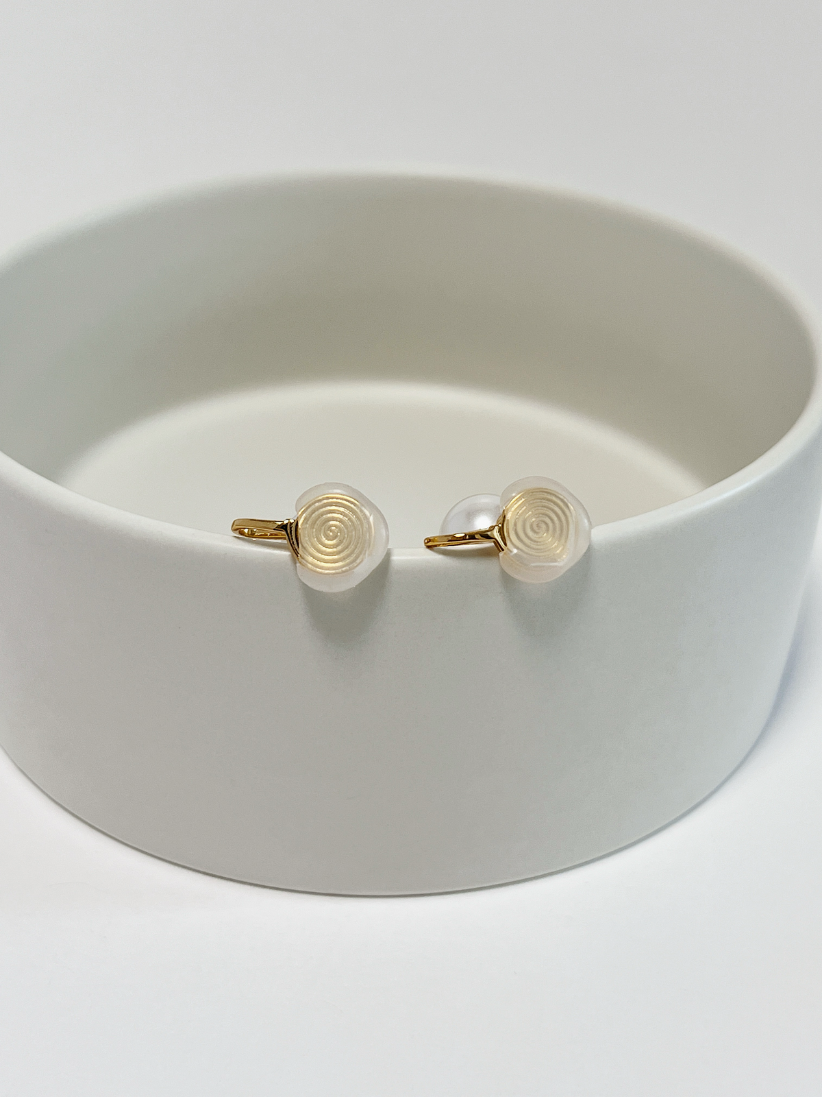 Close-up macro view of the spiraled non-slip silicone comfort pad backings on non-pierced gold pearl clip-on earrings.